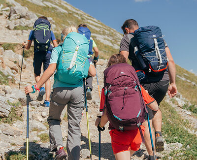 Four hikers scaling a trail with equipment